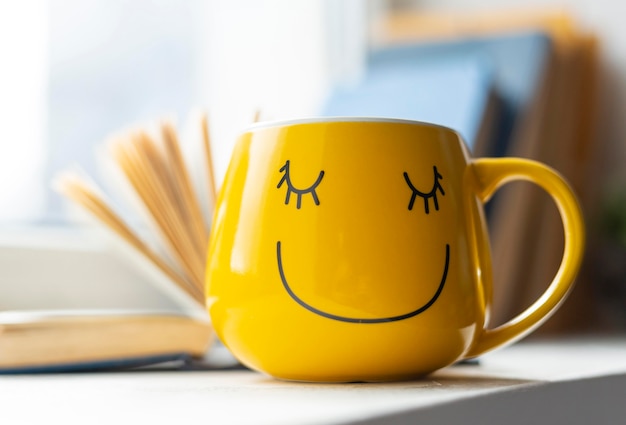 Foto gratuita libro aperto e tazza gialla di smiley