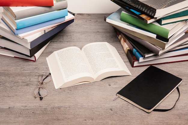 Open book next to stacks of books