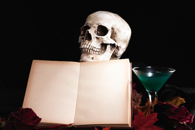인간의 두개골과 음료와 함께 펼친 책
