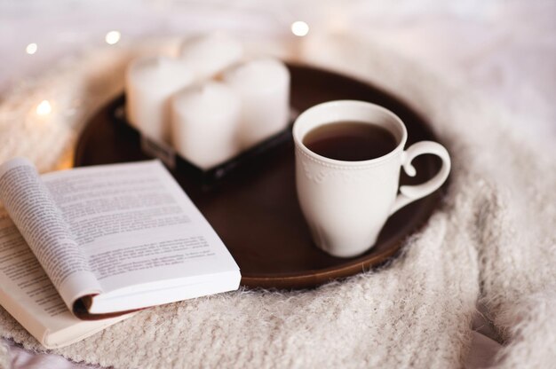 침대에 있는 나무 쟁반에 책 양초와 차 한잔 좋은 아침 여가 시간
