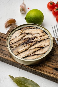 Open can of tinned sardines, sprats fish set, on white stone table background
