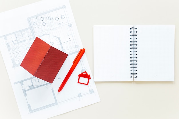 Открытый дневник с планом и моделью дома на столе недвижимости