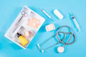 Free photo an open first aid kit with medical equipments on blue background