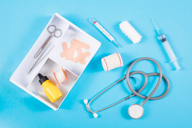 An open first aid kit with medical equipments on blue background