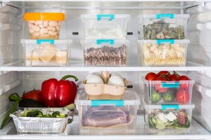 open fridge with plastic food containers and vegetables
