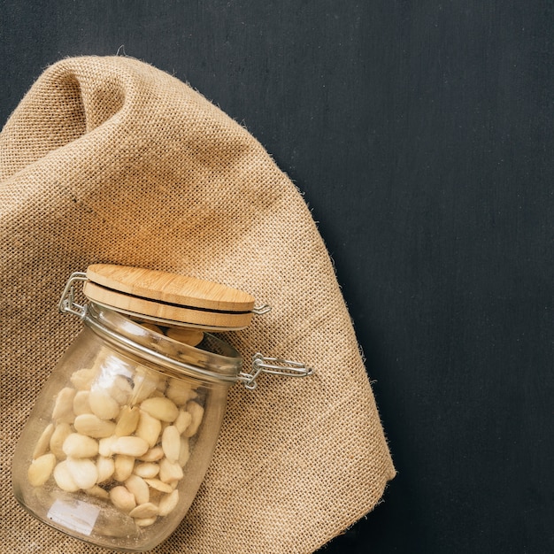 Open glass of nuts on fabric texture