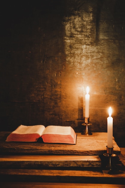 오래 된 오크 나무 테이블에 성경과 촛불을 엽니 다.
