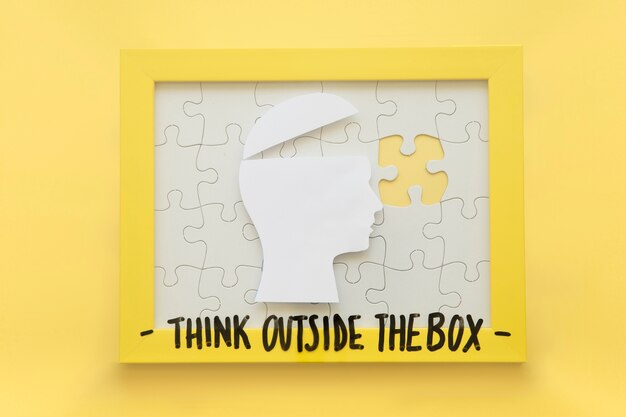 Open human brain and incomplete jigsaw puzzle frame with think outside the box message