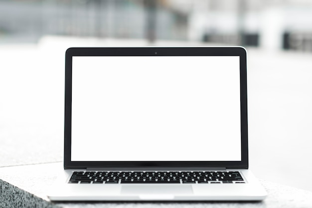 An open laptop showing blank white screen display on bench against blurred background