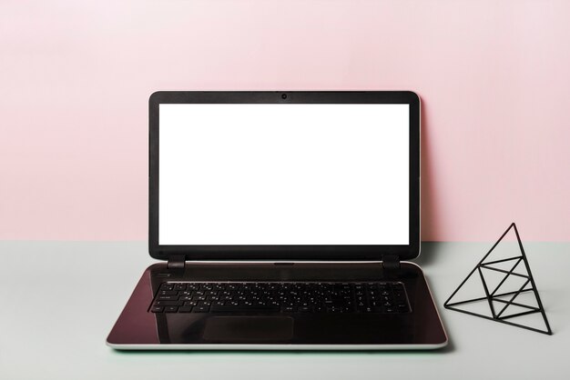 An open laptop with blank white screen against pink background