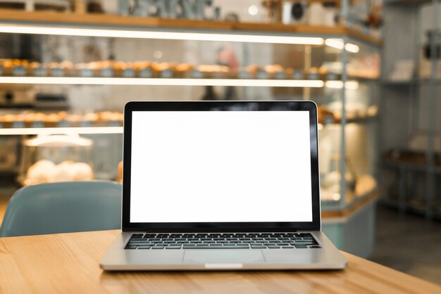 An open laptop with blank white screen display on table in coffee shop