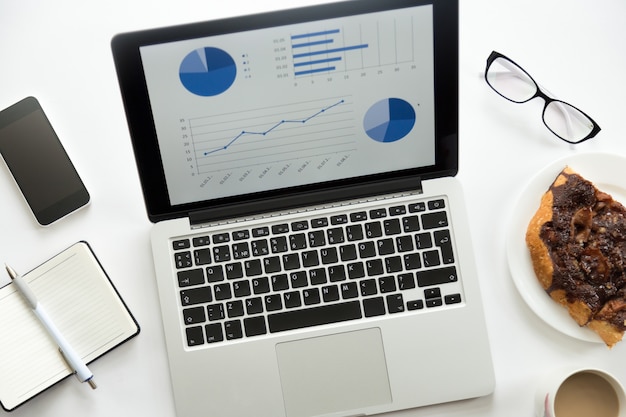 Foto gratuita aprire il computer portatile con un diagramma, occhiali, mobili, forniture per ufficio