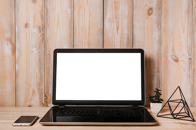 Открытый ноутбук с белым экраном и сотовый телефон на деревянном столе