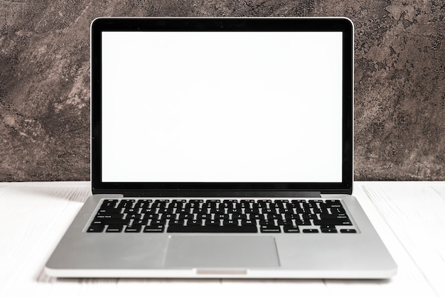 Free Photo an open modern laptop with a white screen on white desk against concrete wall