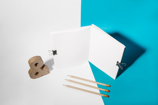 Open notebook attach with bulldog clips; pencils and ampersand symbol