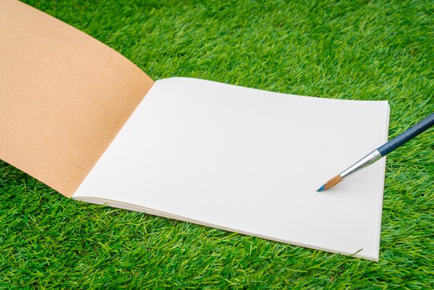 Free photo open notebook on the grass with a pen