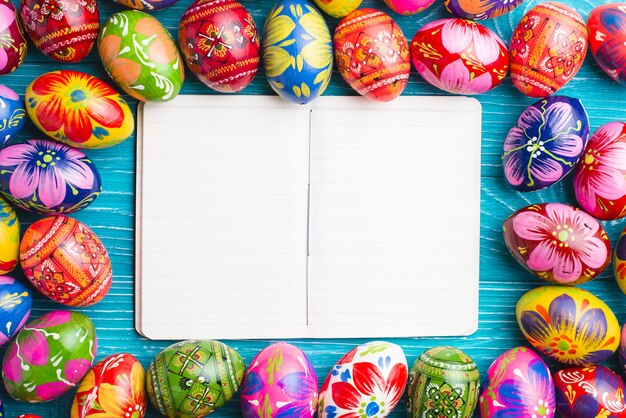 Free photo open notebook surrounded by colorful easter eggs