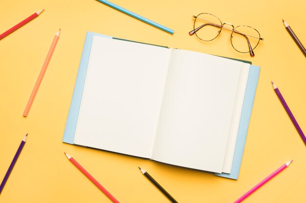 Open notebook with blank pages surrounded by pencils