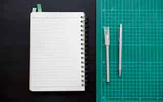 Free photo open notebook with cutting board stationery on dark gray table