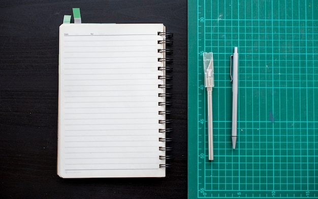 Open notebook with cutting board stationery on dark gray table