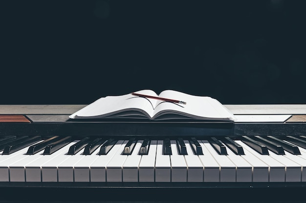 Бесплатное фото Откройте блокнот на клавишах пианино в темном пространстве для копирования