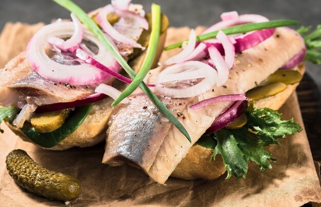 Open sandwich with bread, pickled herring, pickled cucumber and red onion on a paper lining. Danish smorebrod, selective focus and copy space
