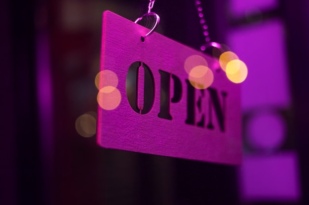 Free photo open sign hanging with purple light