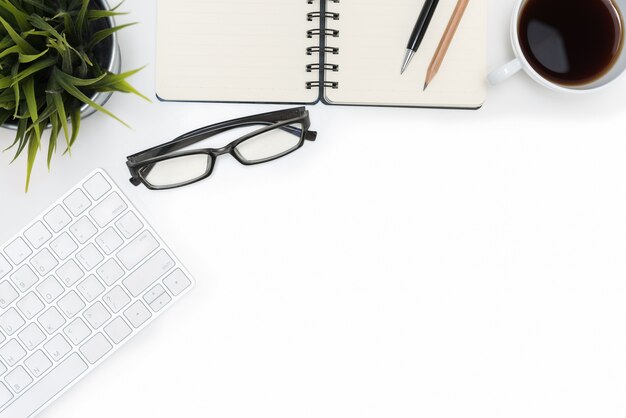 Open spiral blank notebook and computer on white desk