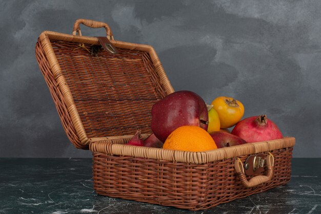 Open suitcase full of fruits on marble wall .