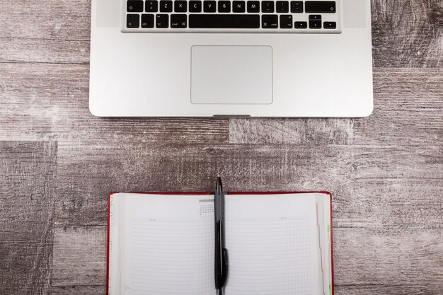 Open writing notebook next to a laptop from above view on a wooden background