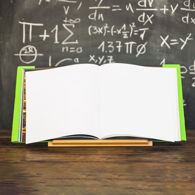 Opened book in book holder near chalkboard