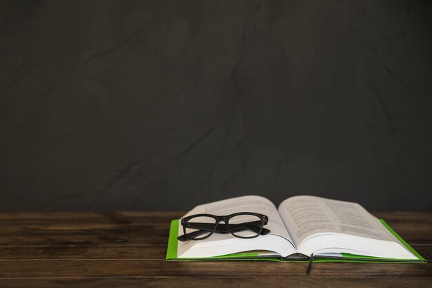 Opened book with glasses on table