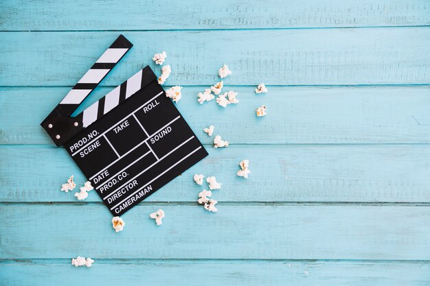 Free photo opened clapperboard near small heap of popcorn