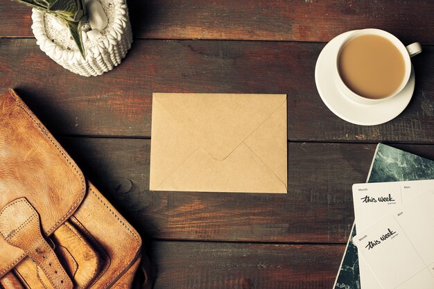 Opened craft paper envelope, autumn leaves and coffee on wooden table