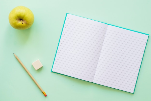 Открыт дневник с яблочным карандашом и резиной