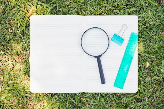 Opened notebook with magnifier on grass