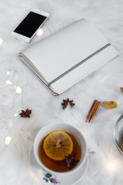 Opened notepad with smartphone near tea cup