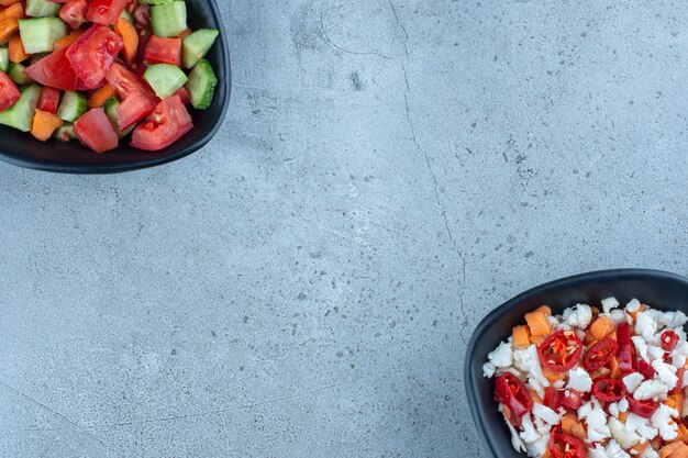 Oppositely aligned salad bowls on marble.