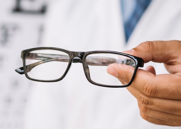 Optician holding eyeglasses with black frame