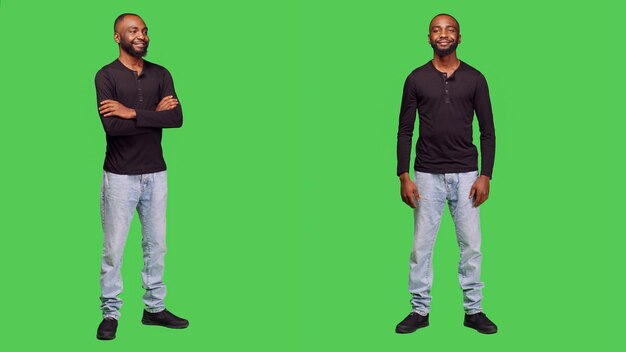 Optimistic adult standing over green screen backdrop, posing in studio and smiling on camera. Happy young model feeling positive wearing jeans and shirt, cheerful stylish person.