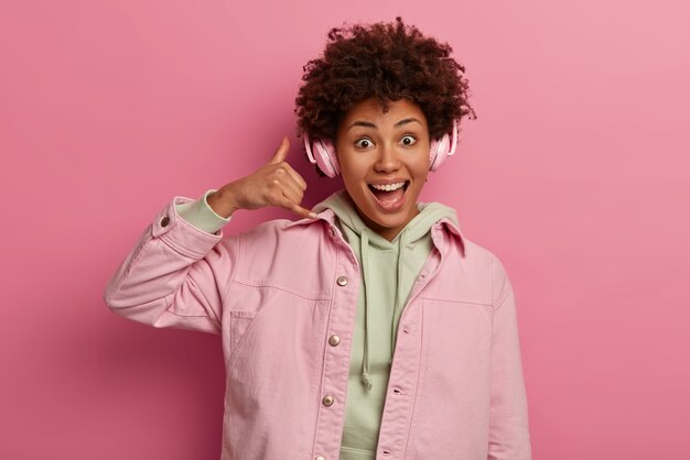 Optimistic dark skinned woman makes call me back gesture