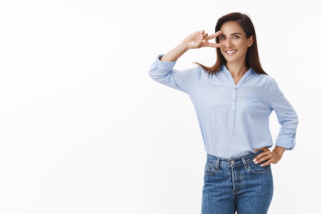 Optimistic lucky goodlooking adult 30s brunette with tattooed arm show peace victory sign near eye smiling upbeat aim success feeling confident encouraged success grin happy white background