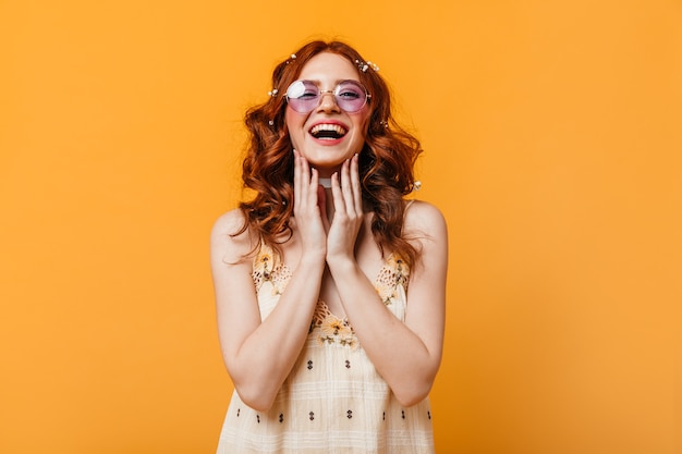 Optimistic woman with curly hair sincerely laughs. Woman in sunglasses and yellow top looking at camera.