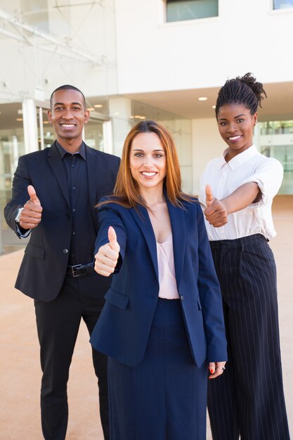 Optimistic young interracial business people showing thumbs-up