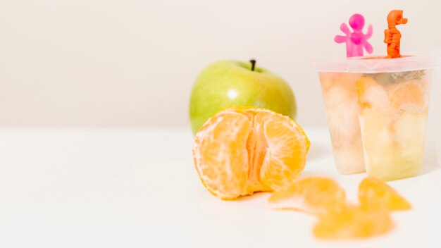 Orange; apple and popsicle mold on desk