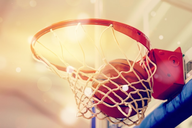 Оранжевый баскетбольный мяч, летящий в баскетбольное кольцо
