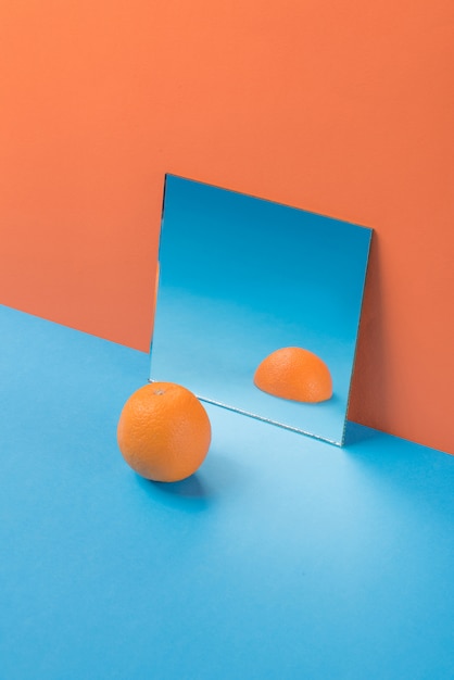Апельсин на синем столе, изолированные на оранжевый