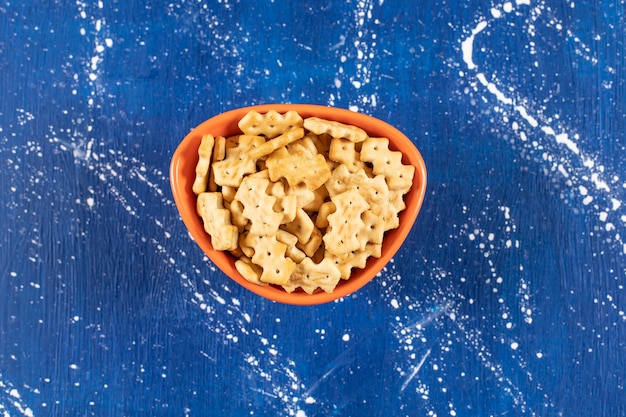 Free photo orange bowl of salty small crackers on marble surface