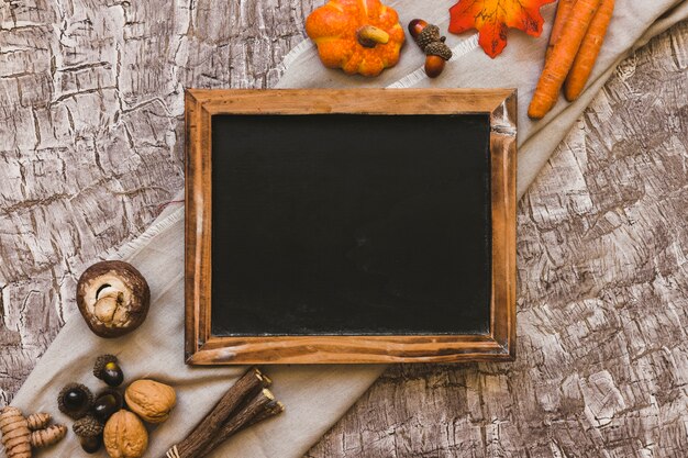 Orange and brown autumn symbols lying near blackboard