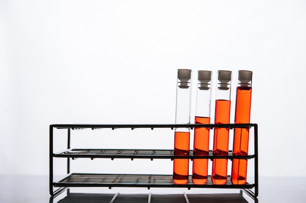 Orange chemicals in a science glass tube arranged on a shelf